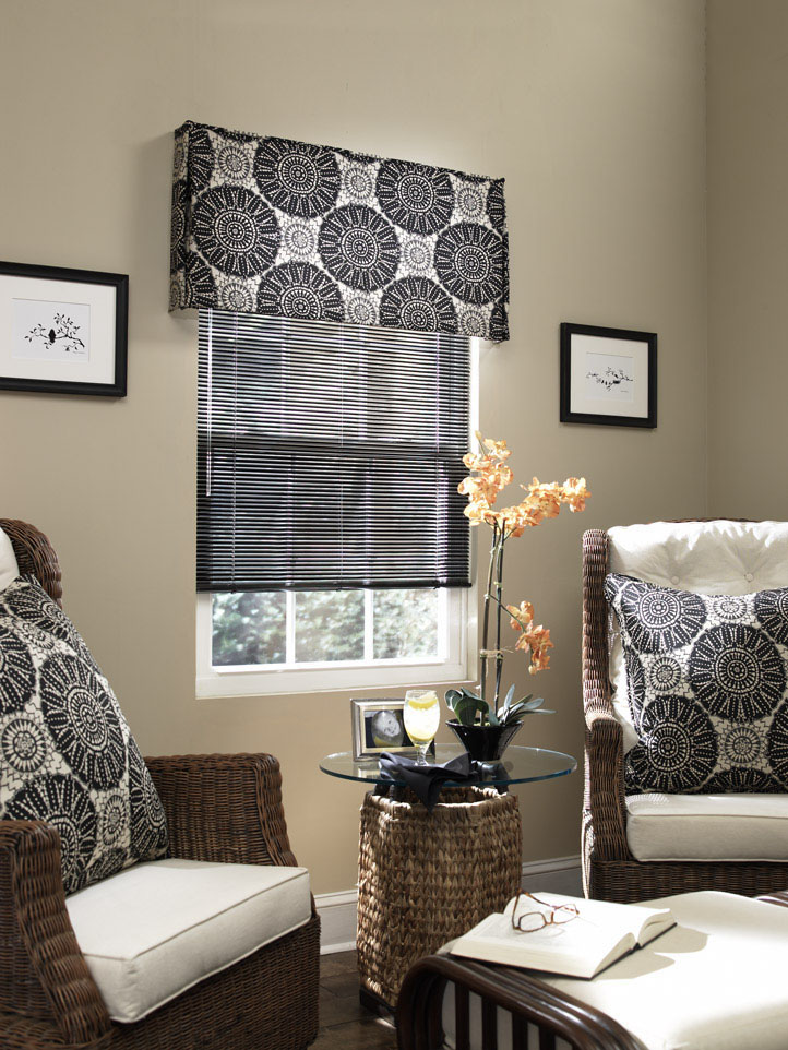 Dark Classic Collection® Aluminum Blinds against tan walls with an Interior Masterpeices® Fabric Cornice with a dark and light geometric pattern and Custom Pillows on brown and white chairs