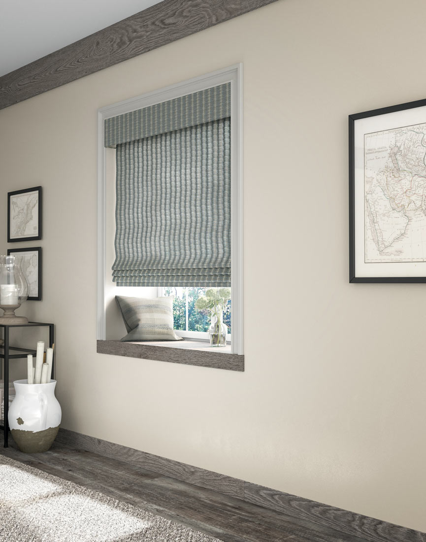 a white and blue Manh Truc® Woven Wood Shade against a tan wall with gray wood floors and window bottom