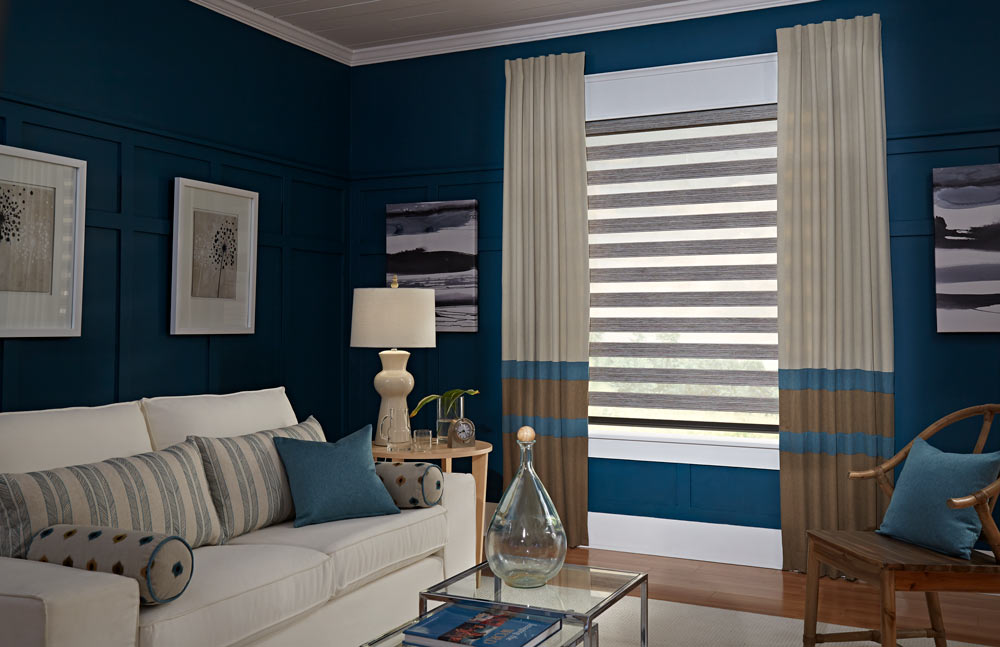 brown Allure® Transitional Shade against a dark blue wall with tan, brown, and blue striped Interior Masterpieces® Draperies behind a couch with matching custom Pillows