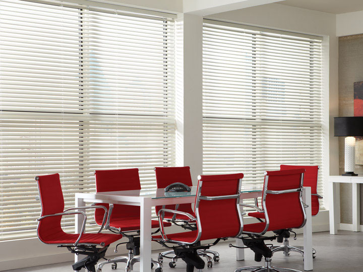 Several White Classic Collection® Aluminum Blinds in an office with red chairs and a table