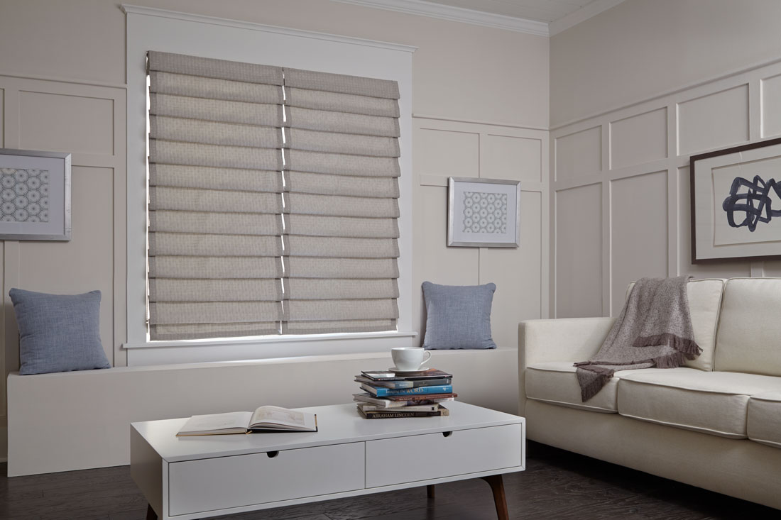 Two gray Interior Masterpieces® fabric shades in a white room with couch and custom accent pillows