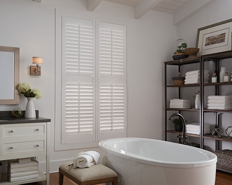 White Parke® Shutters in a bathroom with a tub and shelves next to them