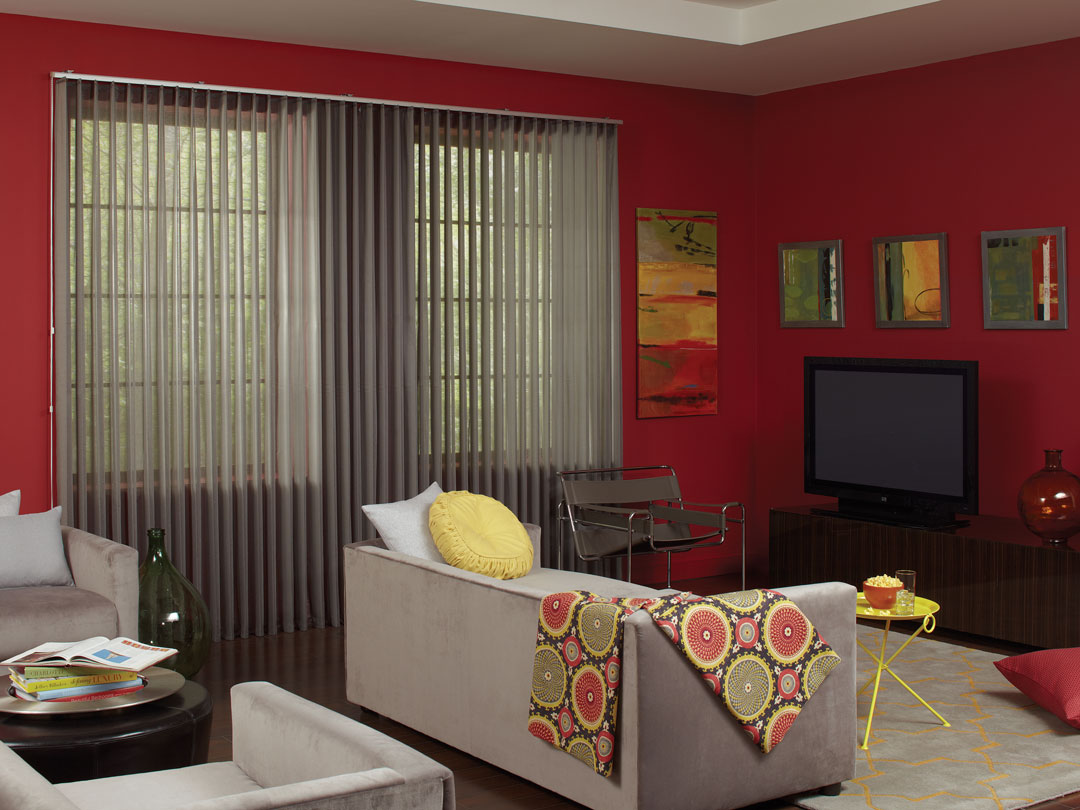 Gray Sheer Visions® Vertical Blinds in a large window in a room with red walls and a light gray couch