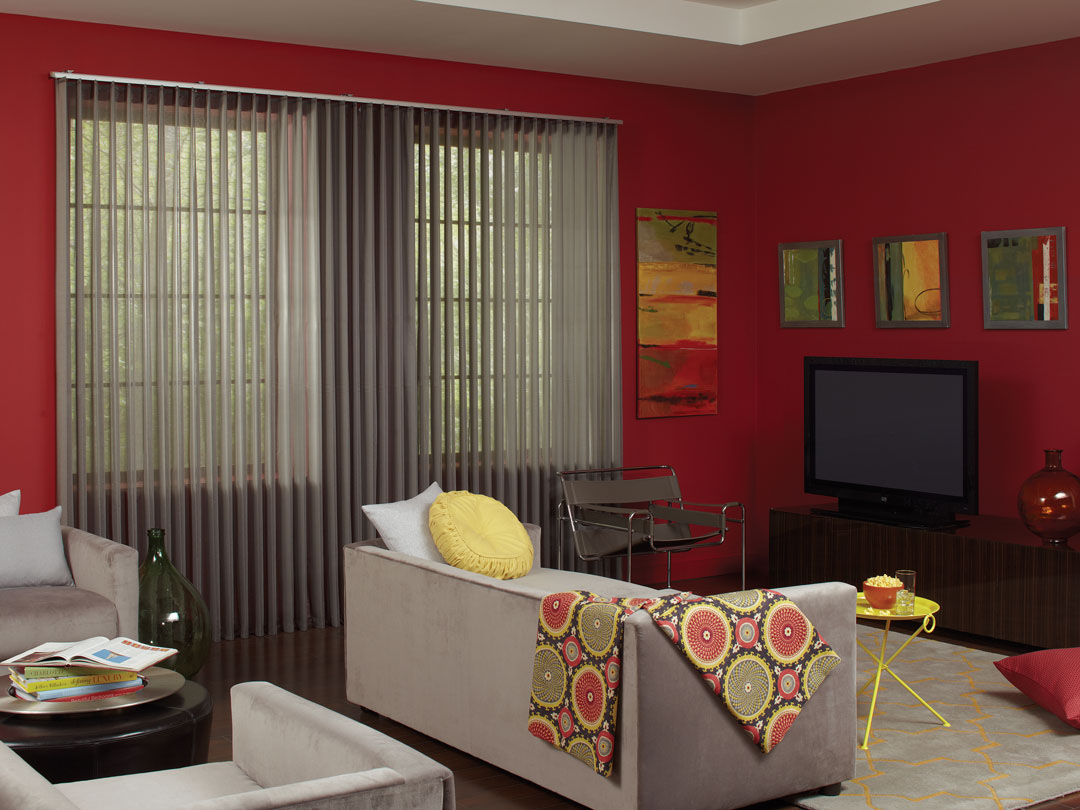 Gray Sheer Visions® Vertical Blinds in a large window in a room with red walls and a light gray couch