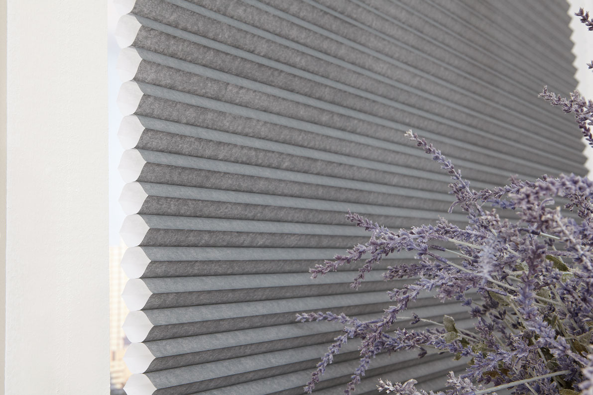Parasol® Cellular Shade in a gray material with purple flowers next to it