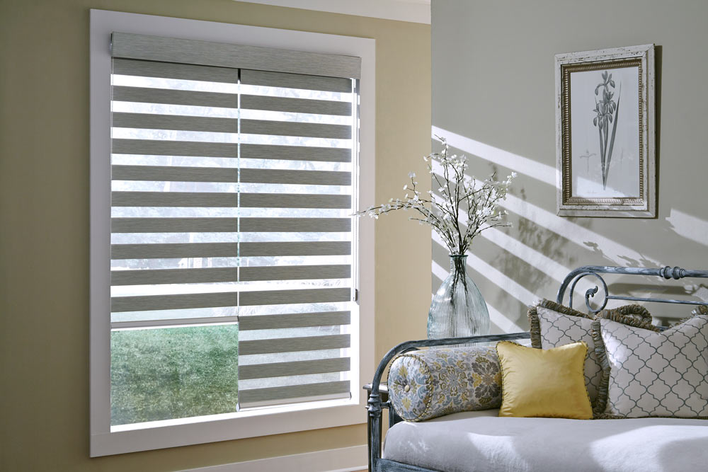 Two gray Allure® Transitional Shades in a window next to a bench with a yellow and gray floral pattern pillow and solid yellow Interior Masterpieces® Custom Pillows