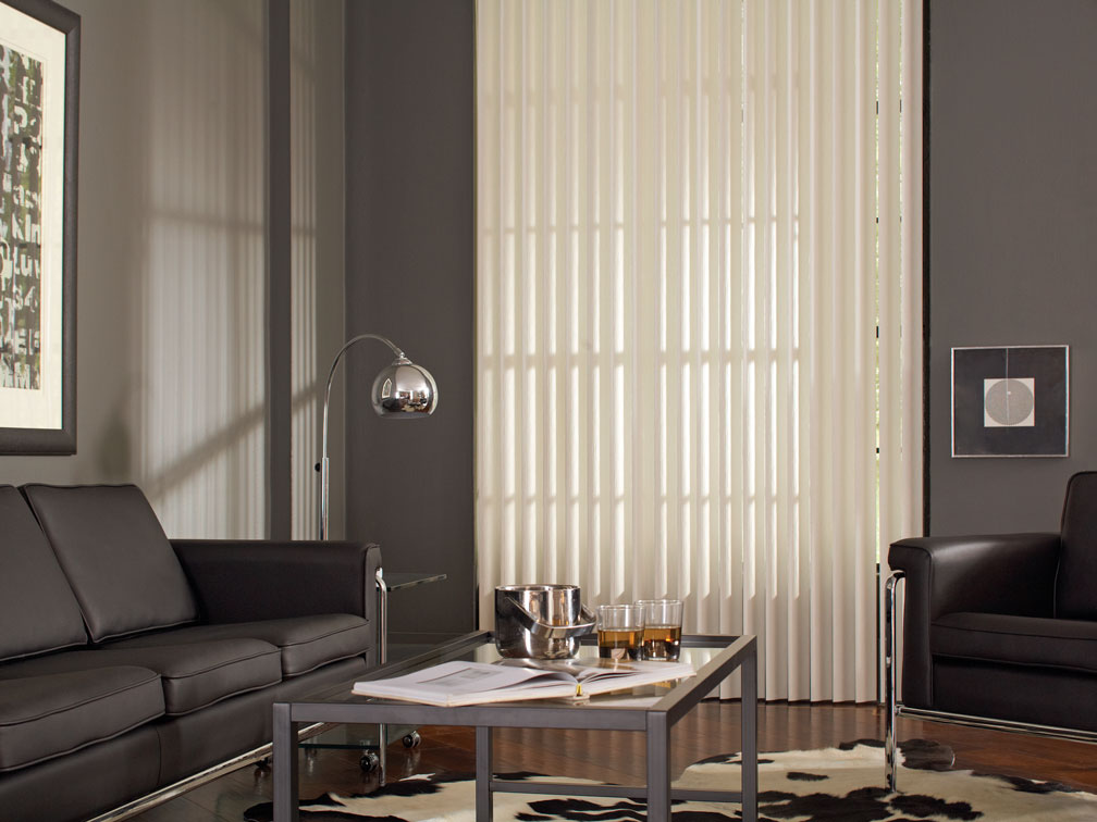 White Discoveries® Vertical Blinds in a room with gray walls and black furniture