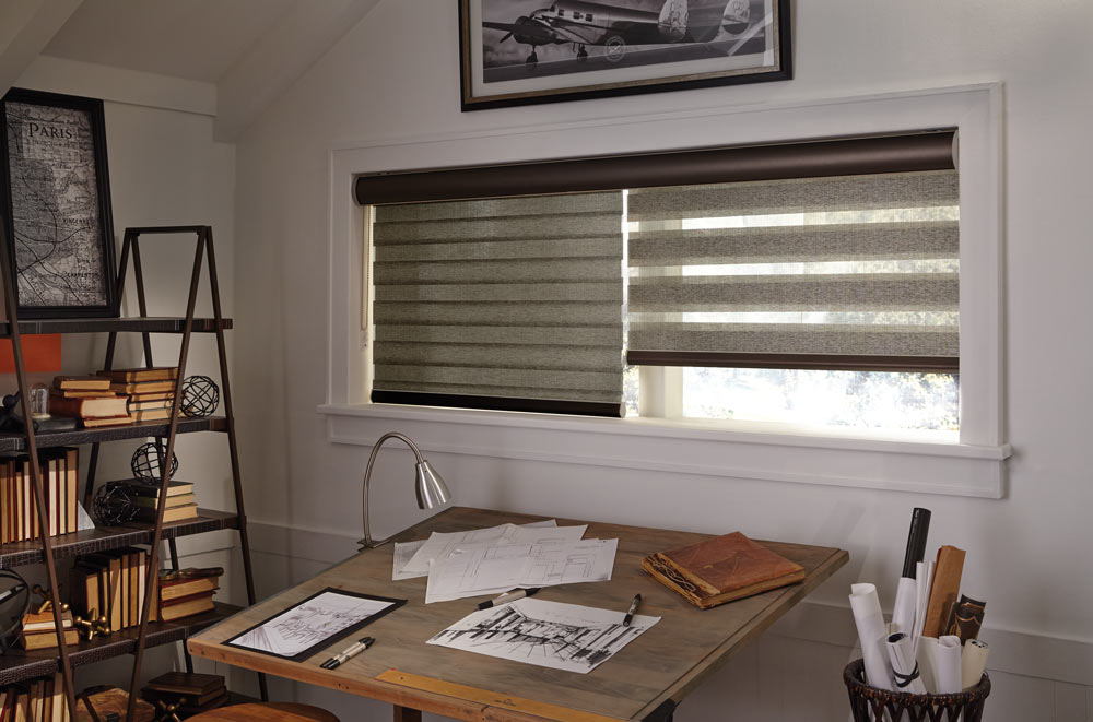 wide window with brown Allure® Transitional Shades in one wide black cassette with black bottom rails behind a desk