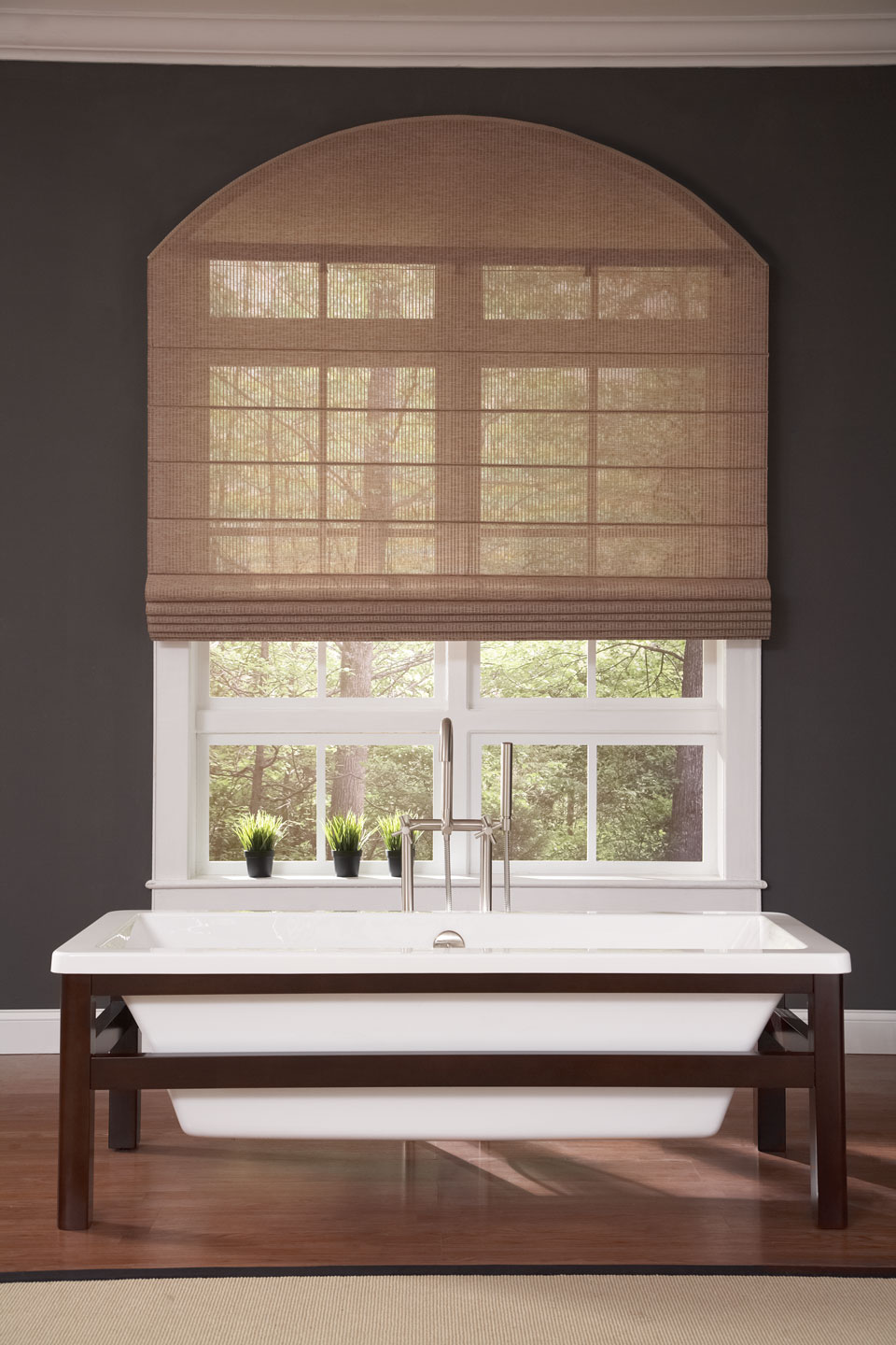 A tan Genesis® Flat Roman Shade behind a sink in a bathroom setting