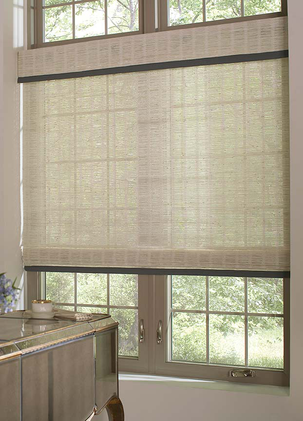An ivory traditional flat woven wood shade and valance hang in the casement window of a classy home office.