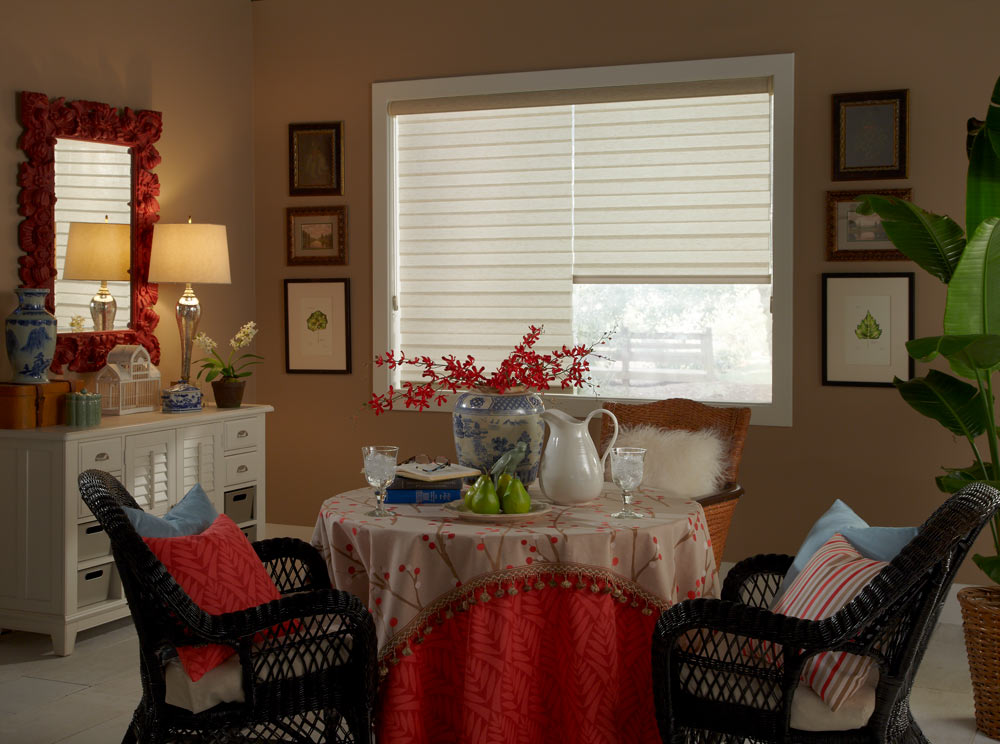 two cream colored Allure® Transitional Shades behind a small table with tan and red Interior Masterpieces® Table clothes with flowers on it surrounded by black chairs and accenting Custom Pillows