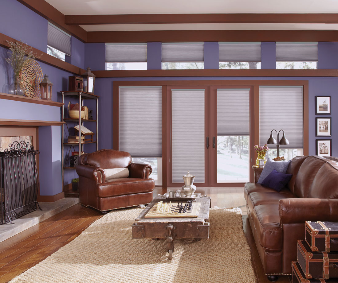 Room with 2 large windows flanking two large glass doors with Parasol® Cellular shades in them and smaller windows with motorized Auto-Lift Cellular Shades around the top of the room