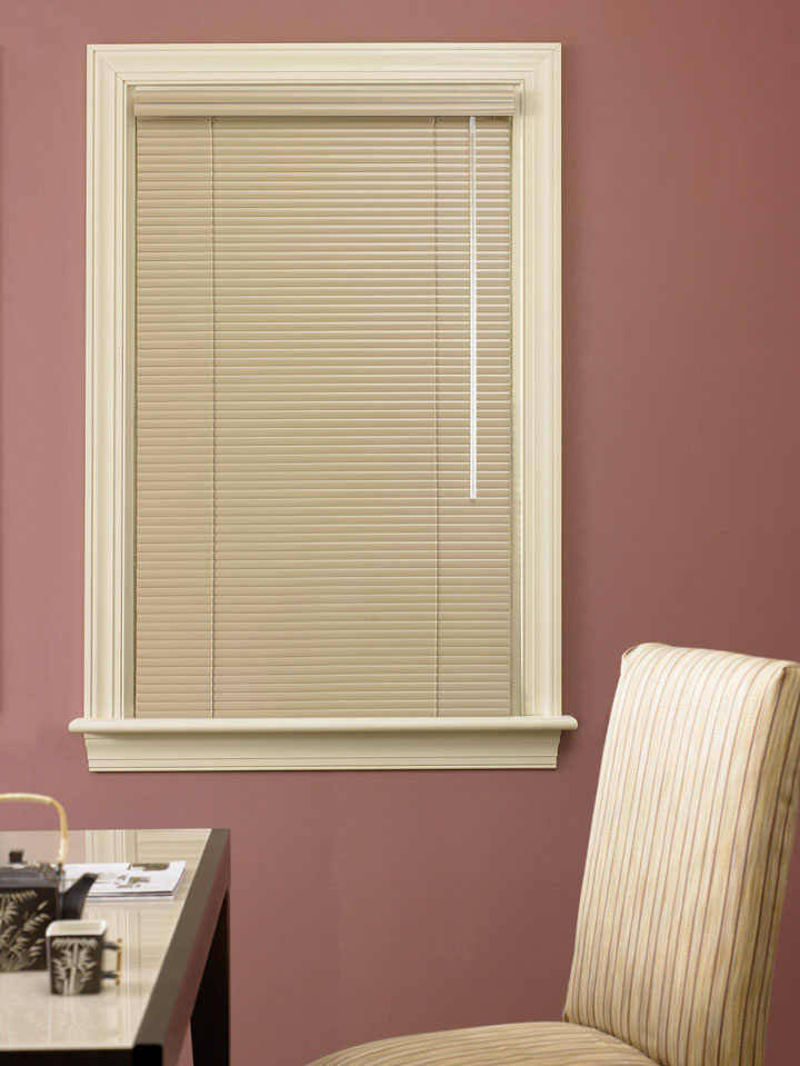 Tan color Classic Collection® Aluminum Blind against a reddish clay colored wall with a table and chair in front