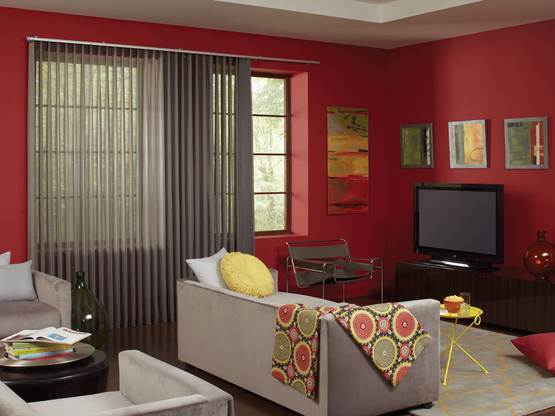 Gray Sheer Visions® Vertical Blinds in a large window in a room with red walls and a light gray couch