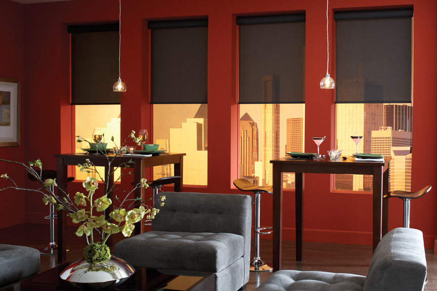 A dining room with dark, light filtering Genesis® Roller Shades