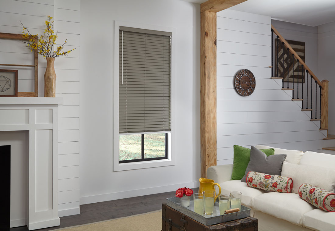 two large brown WonderWood® Wood Blinds in a room with a gray couch and white chairs that have Interior Masterpieces Custom Pillows