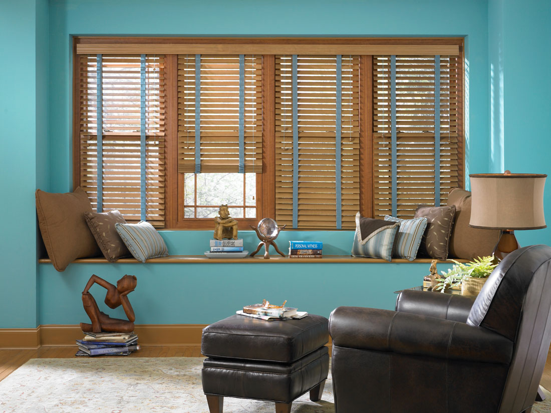 four brown Heartland Woods® Wood Blinds with blue Banding in a room with blue walls and a black chair