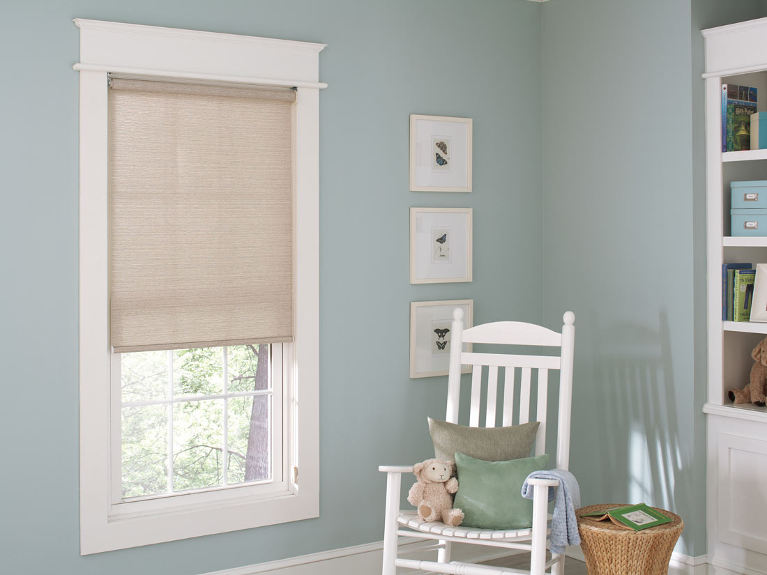 tan Genesis® Roller Shades against blue walls with a white chair nearby and a stuffed animal on it