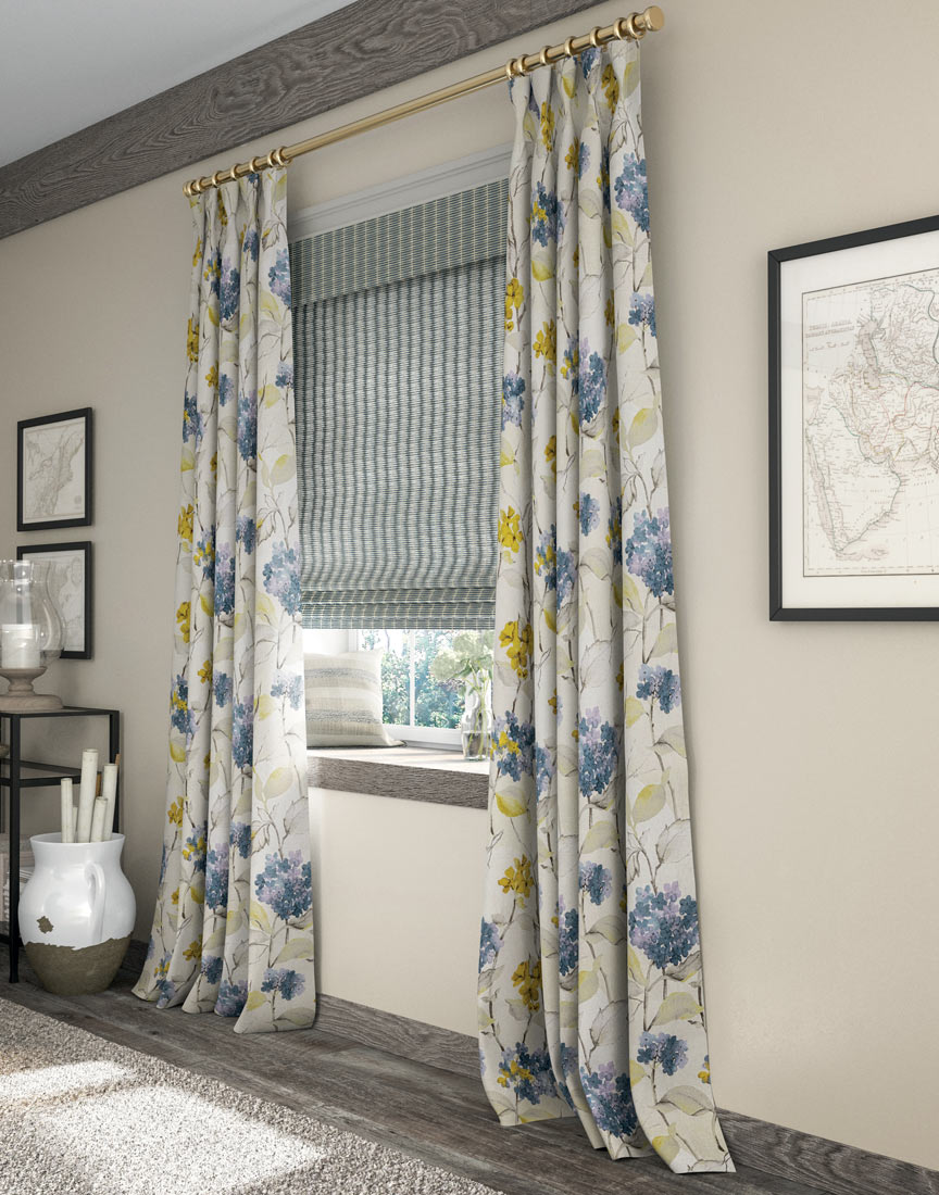 blue and white Manh Truc® Woven Wood Shade & tan, blue and yellow floral patterned Interior Masterpieces® Draperies hanging on a golden rod and rings