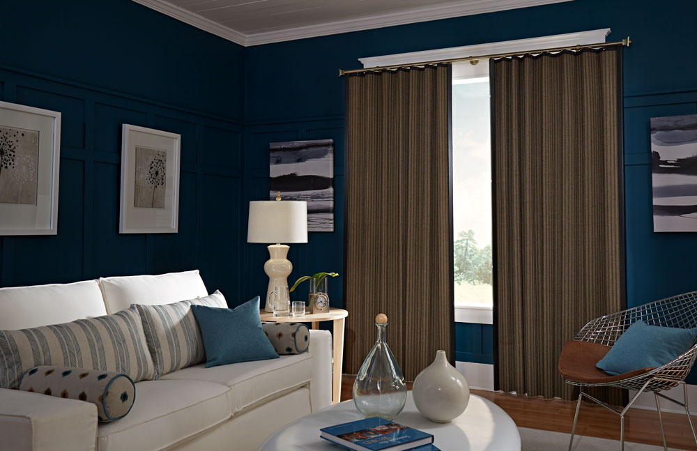 Dark brown Manh Truc® panel drape in a room with blue walls a white couch and accenting Interior Masterpieces® pillows