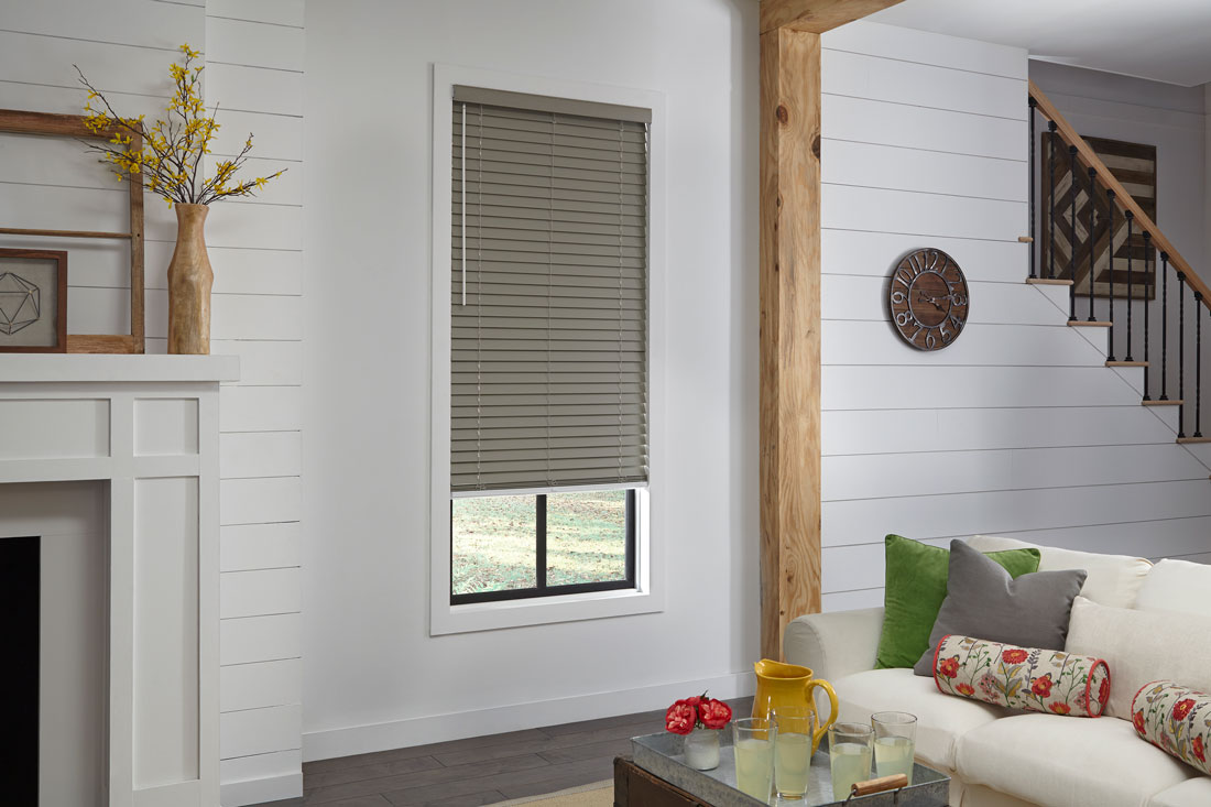 Brown Wonderwood® Wood Blinds on a white wall with a couch that has Interior Masterpieces® custom pillows on it