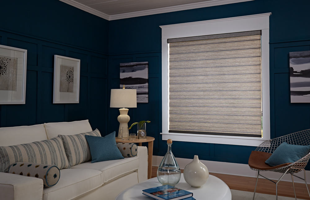 large brown Allure® Transitional Shade against a dark blue wall with accenting Custom Pillows on a cream colored couch in the foreground