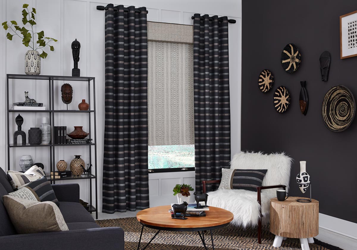 Dark Interior Masterpieces® grommet panels in front of a tan fabric wrapped cornice and fabric shade in a room with chairs and custom Interior Masterpieces® pillows