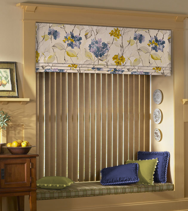 Blue and green floral valance accent vertical blinds hanging in a window with a bench box cushion accented with blue and green pillows.