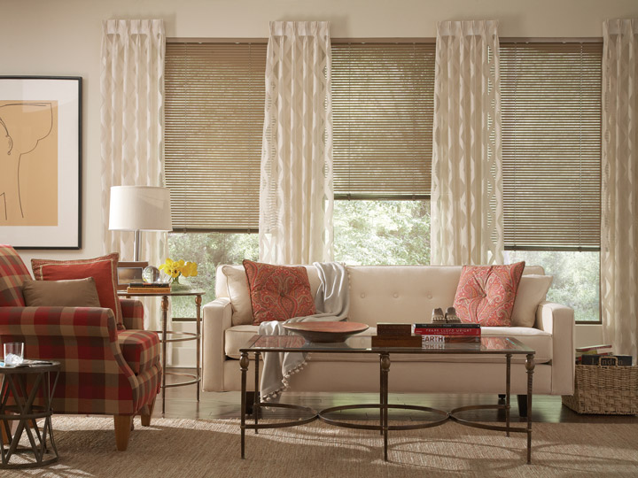 Light brown Classic Collection® Aluminum Blinds & Interior Masterpeices® cream colored Draperies and light red floral Custom Pillows on a light colored couch