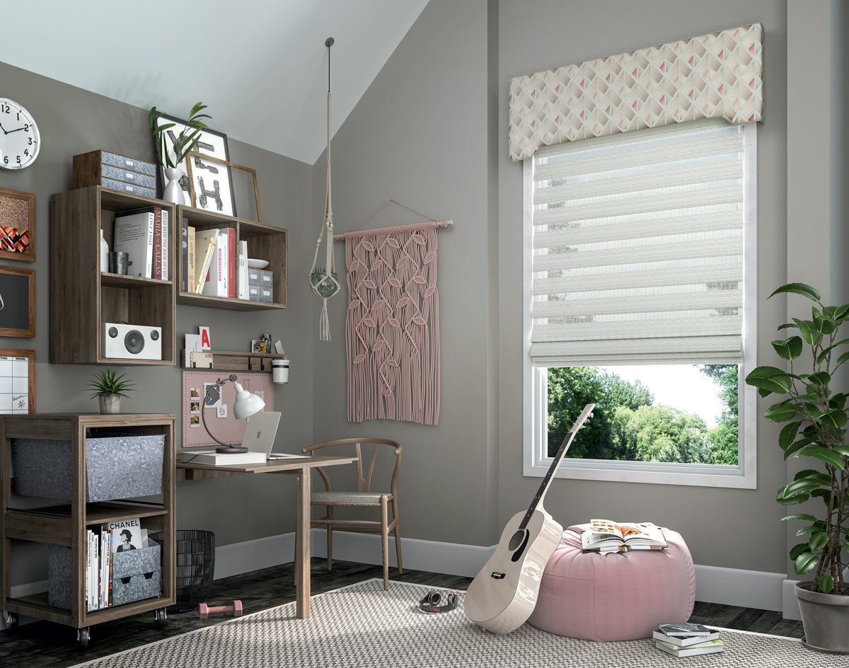 White Manh Truc® Woven Wood Shade with pink white and gray Interior Masterpieces® Fabric Cornice with a geometric pattern against gray walls and behind a pink bean bag chair and guitar