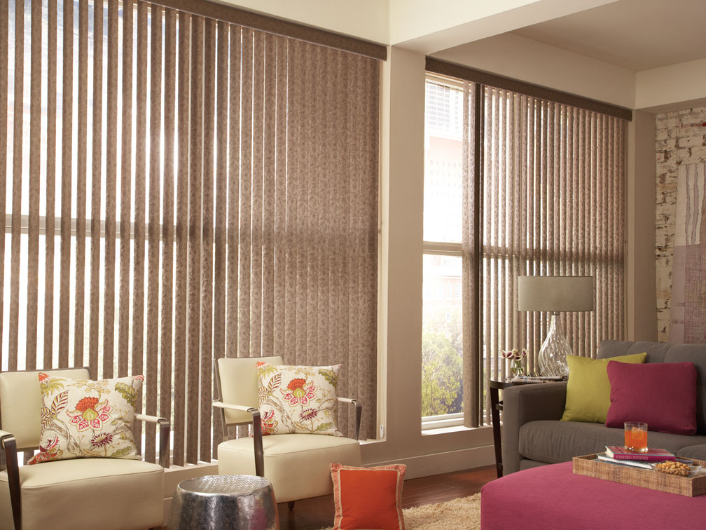 2 large brown Discoveries® Vertical Blinds with chairs and a sofa sitting in front that have Sheer Visions® material custom pillows