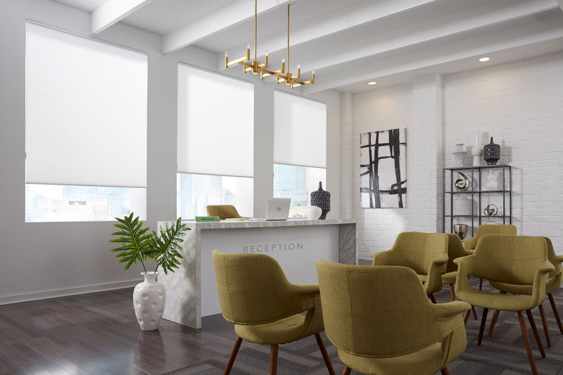 three white colored Parasol® Cellular shades behind a reception desk in an office setting