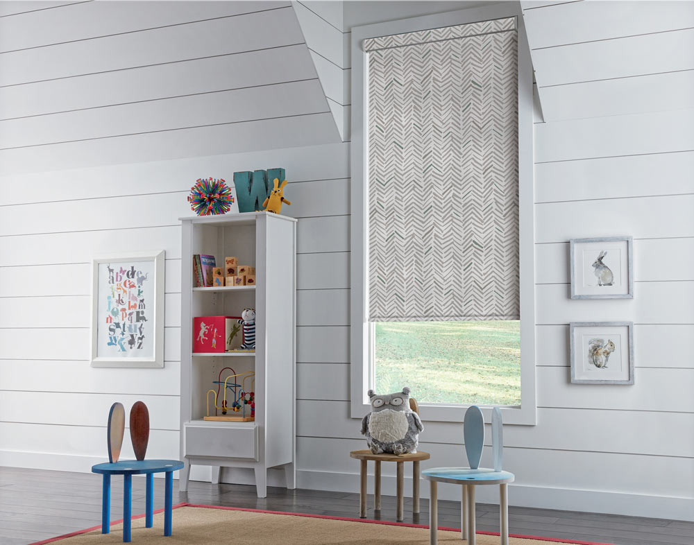 white Genesis® Cassette Roller Shade with a gray and green chevron pattern in a child's room with tiny chairs and a stuffed owl