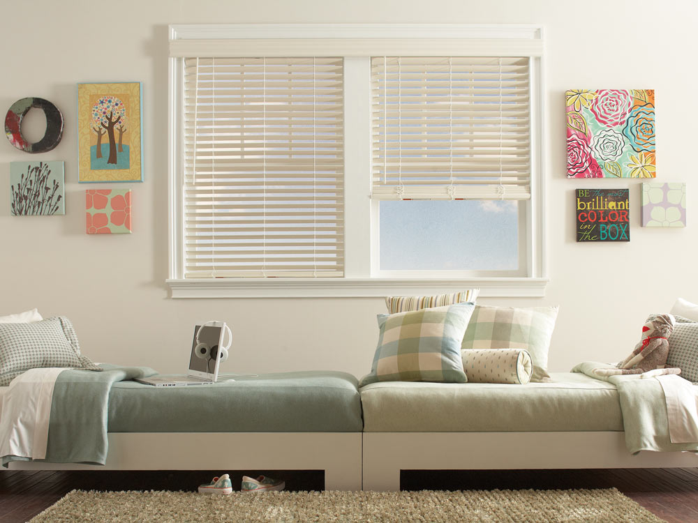 Two white Fidelis® Composite Wood Blinds side by side above to beds laying end to end with varying shades of green Interior Masterpieces® Custom Bedding
