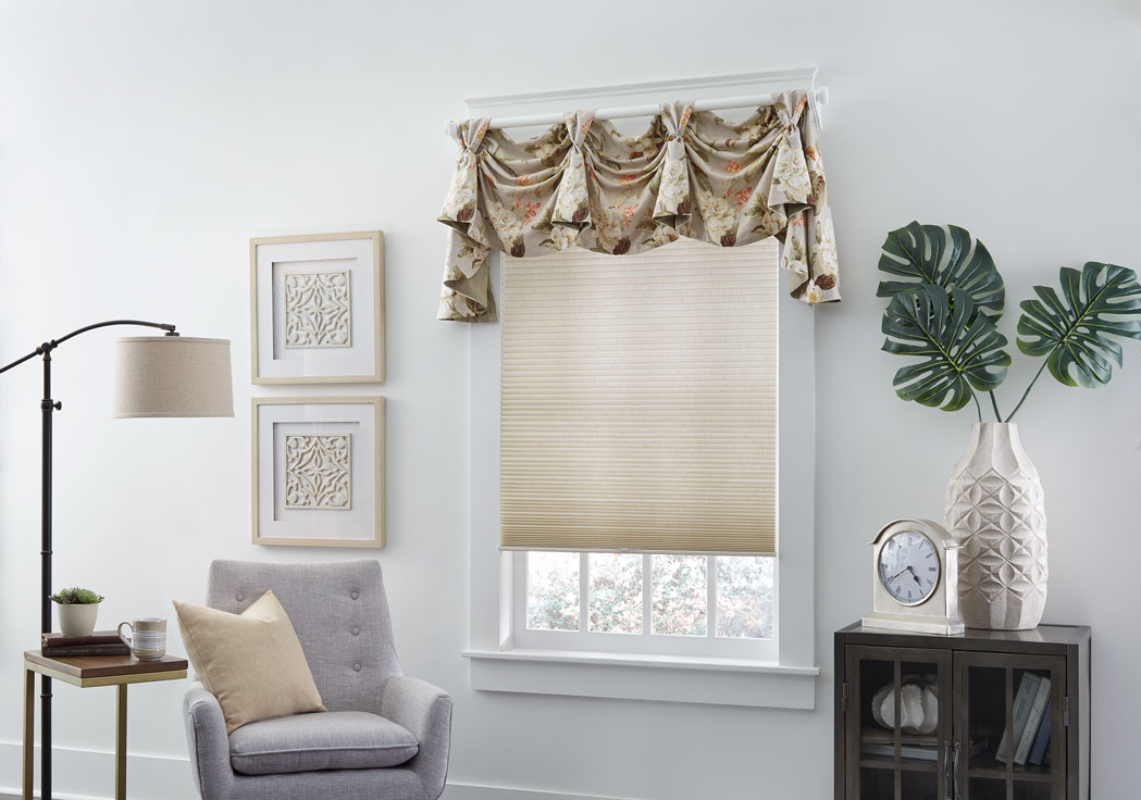Parasol® Cellular shade in a tan material with a custom Interior Masterpieces® valance in a floral tan materian with custom Decorative Hardware