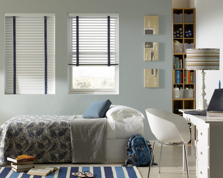 white Classic Collection® Aluminum Blinds with blue Decorative Tape behind a bed with Interior Masterpieces® bedding in blue and grays