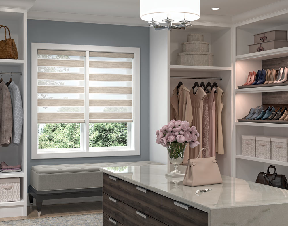 two light brown Allure® Transitional Shades in a closet with clothes hanging nearby and a dresser with flowers in the foreground