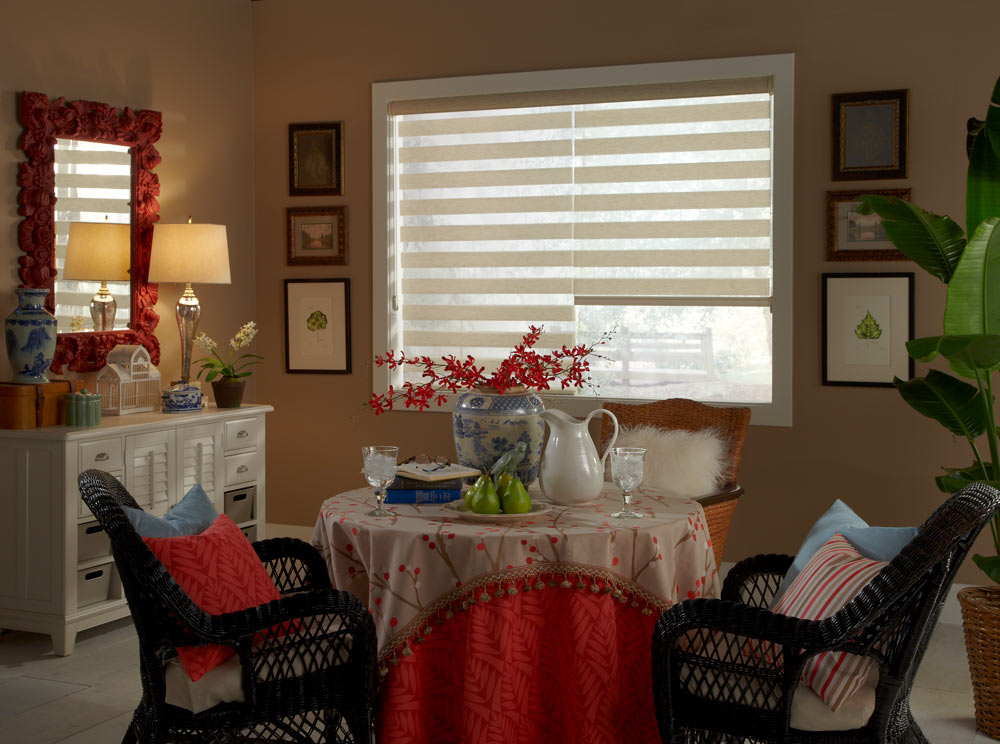 two cream colored Allure® Transitional Shades behind a small table with tan and red Interior Masterpieces® Table clothes with flowers on it surrounded by black chairs and accenting Custom Pillows