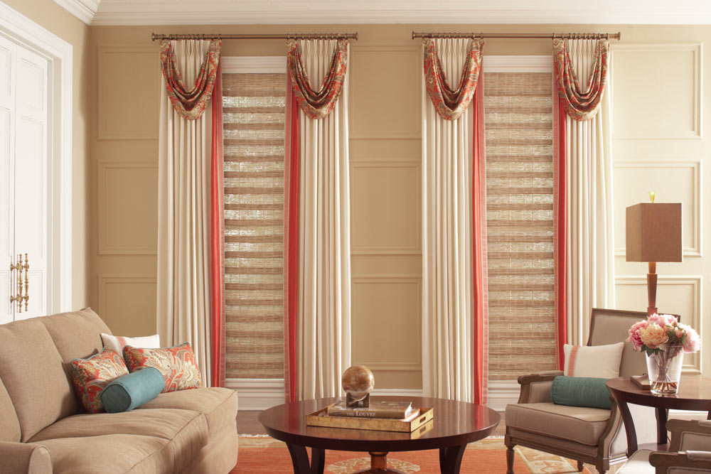 Two long light brown Manh Truc® Woven Wood Shades with tan and red Interior Masterpieces® Draperies on bronze Custom Hardware