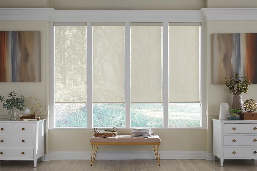 Four light cream colored Genesis® Cassette Roller Shades showing varying opacities with the lightest on the left and the darkest on the right