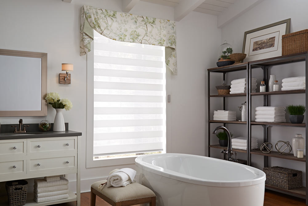 one large white Allure® Transitional Shade with an Interior Masterpeices® green and white floral Fabric Valance in a bathroom behind a stand alone tub and dark shelving
