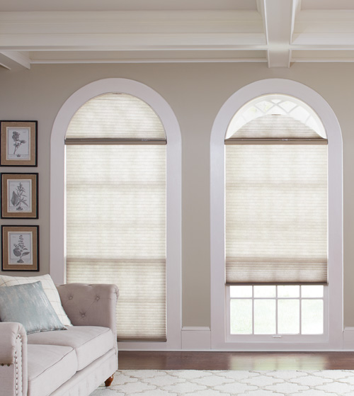 Custom Cellular shades adorn two arched windows, one with shades closed one with shades open showing the separately operable shade covering the arch.