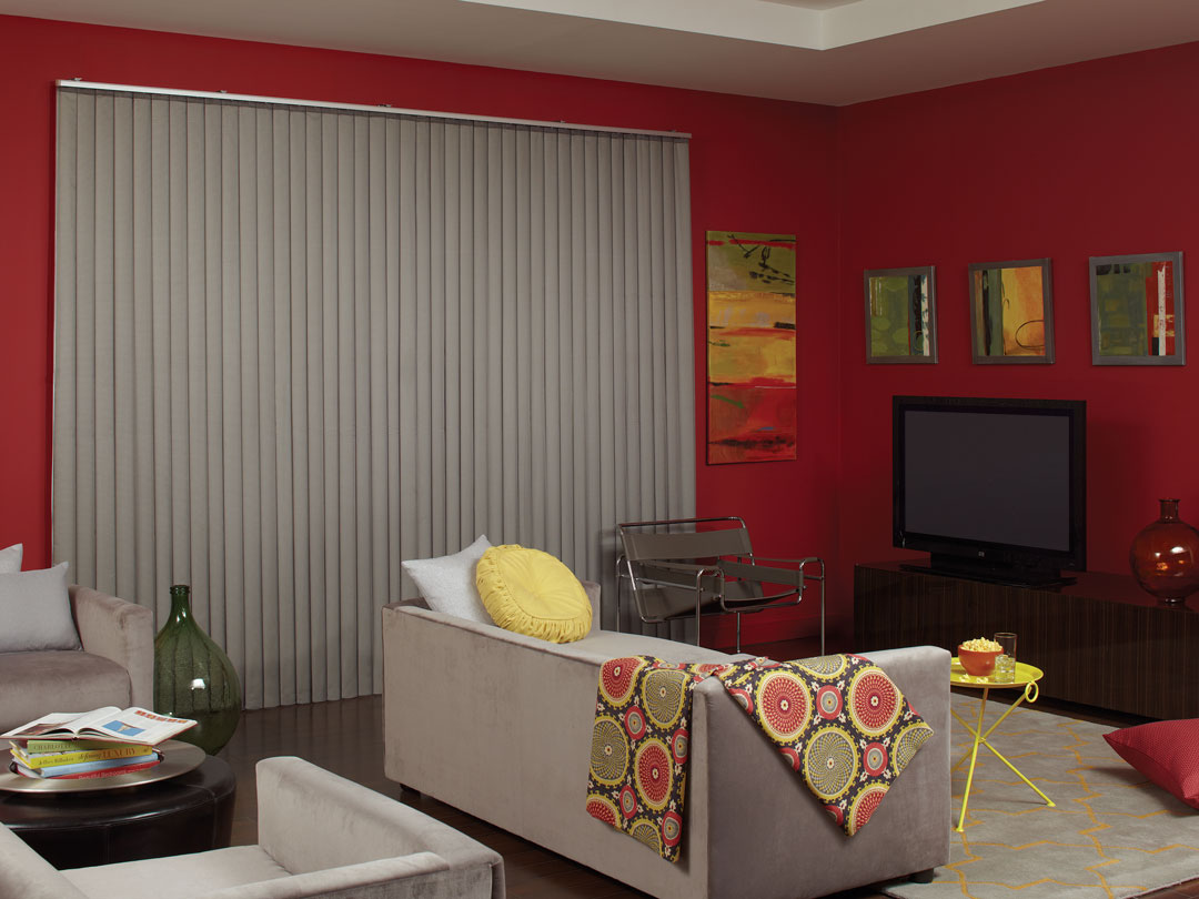 Gray Sheer Visions® Vertical Blinds in a large window in a room with red walls and a light gray couch