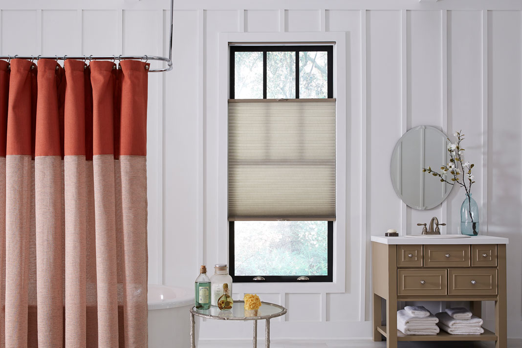 tan Parasol® Cellular Shades in a bathroom with a red shower curtain and brown vanity