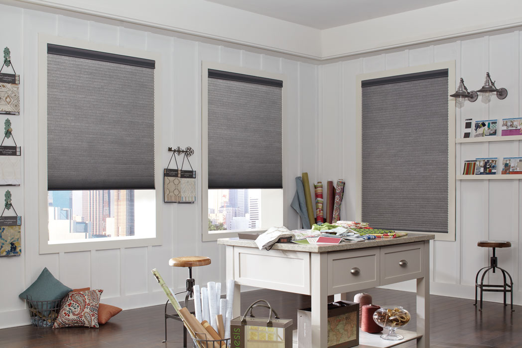 3 Parasol® Duo-Lucent Cellular Shades with dark materian in a room with lightly colored walls and desk