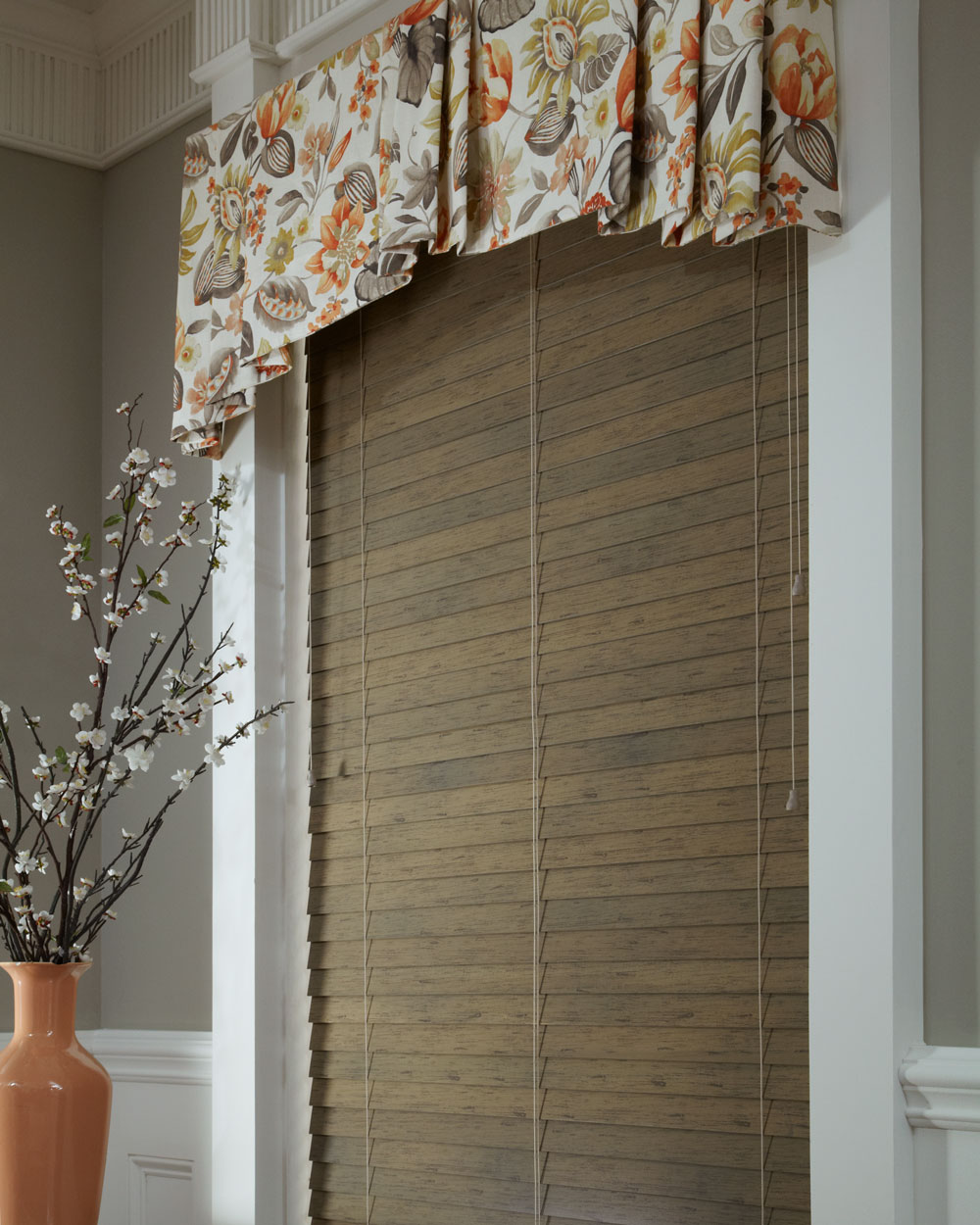 Dark brown Heartland Woods® Wood Blind & Interior Masterpieces Fabric Valance in a white, tan, and orange floral pattern