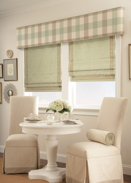 windows with Green Interior Masterpieces® Hobbled Roman Fabric Shades with light brown trim and a tan, brown and green striped Custom Cornice spanning the width of both windows