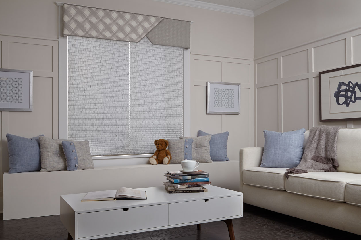 Two Parasol® Cellular shades with the Accu-Rise lifting system in a child's room behind a teddy bear and bench with a Custom Cornice hanging over both shades