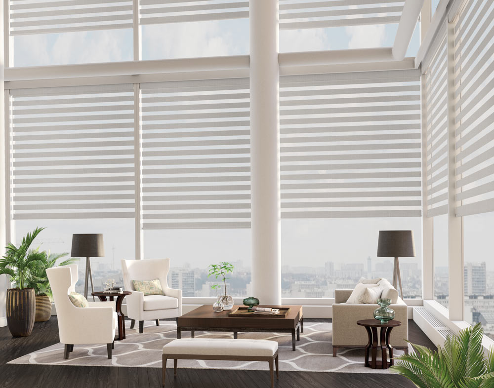 Several large tan colored Allure® Transitional Shades in a high rise apartment with white chairs and a brown table in the foreground