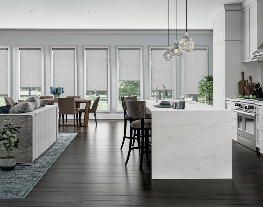 several tall gray Genesis® Cassette Roller Shades in a dining area with brown chairs and a table in front and a kitchen in the foreground